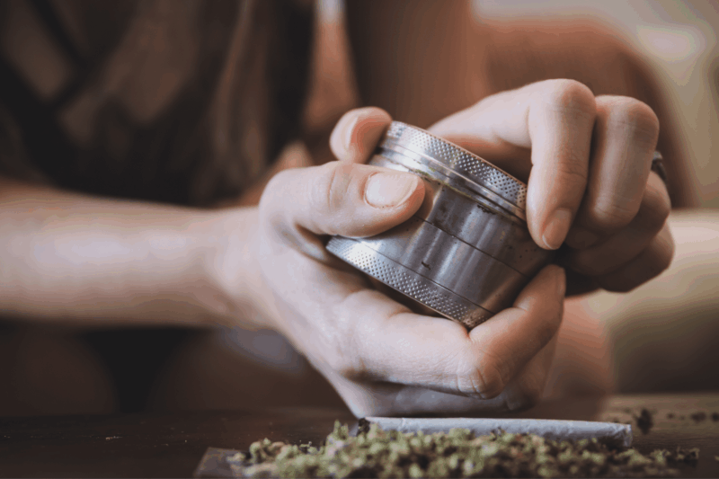 a person putting herb into a weed grinder
