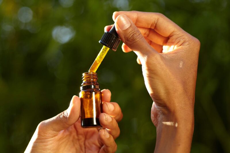 A woman holding a CBD oil bottle with dropper