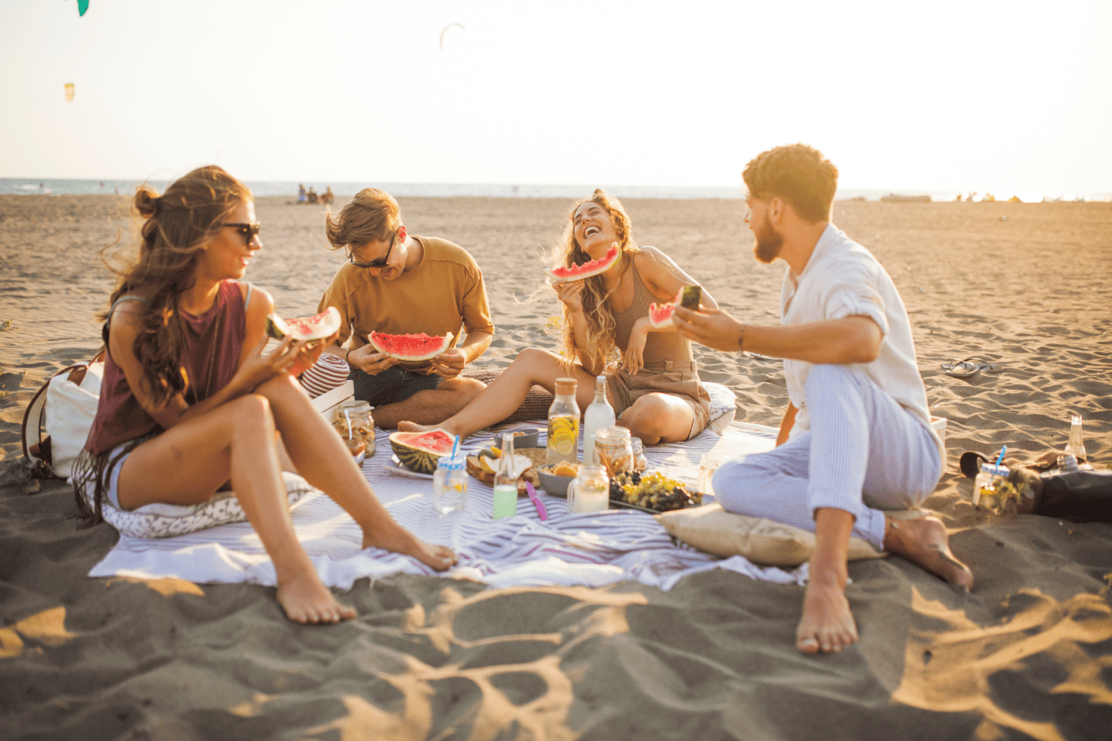 a group of friends eating watermelon on the beach