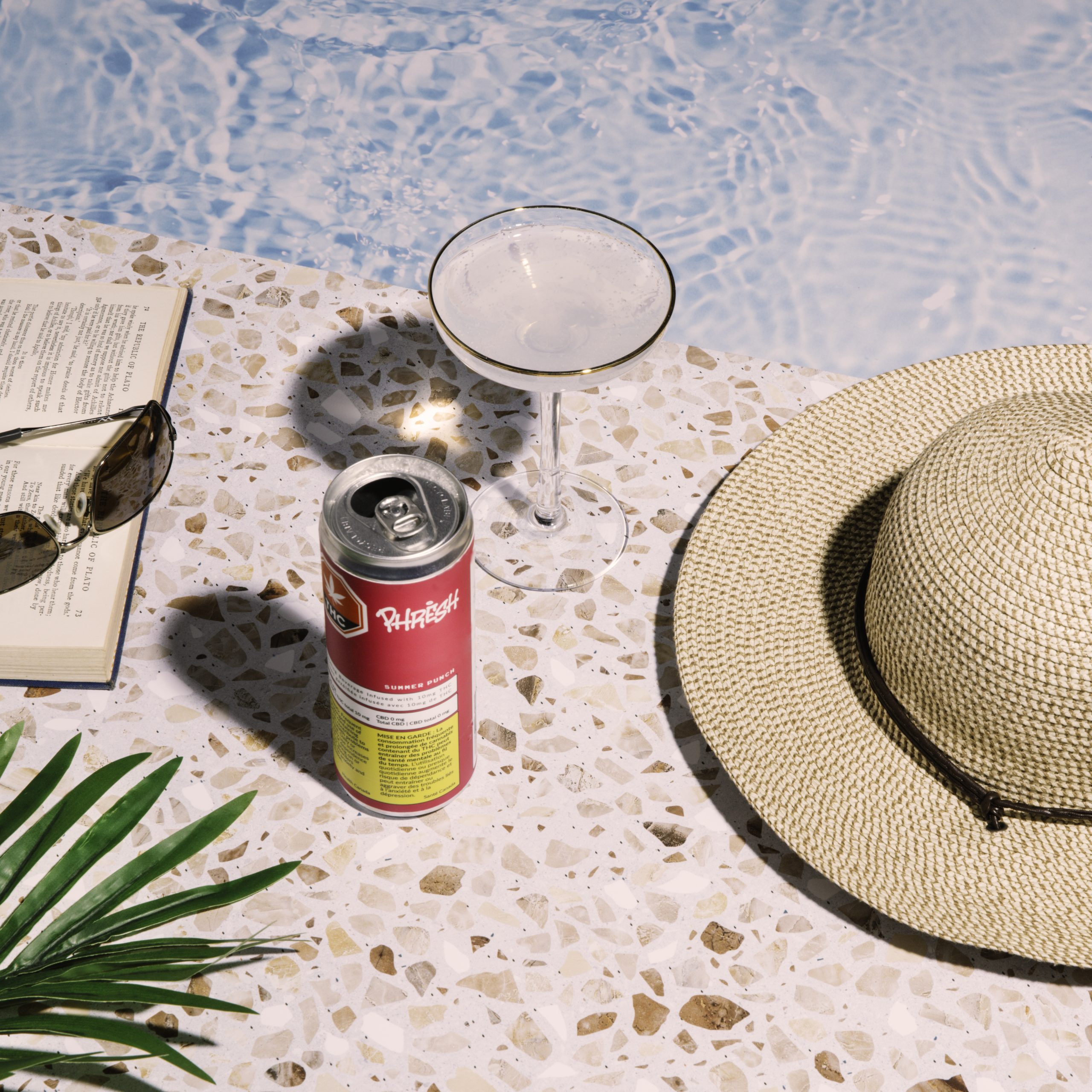 an open book and a cannabis beverage next to a pool