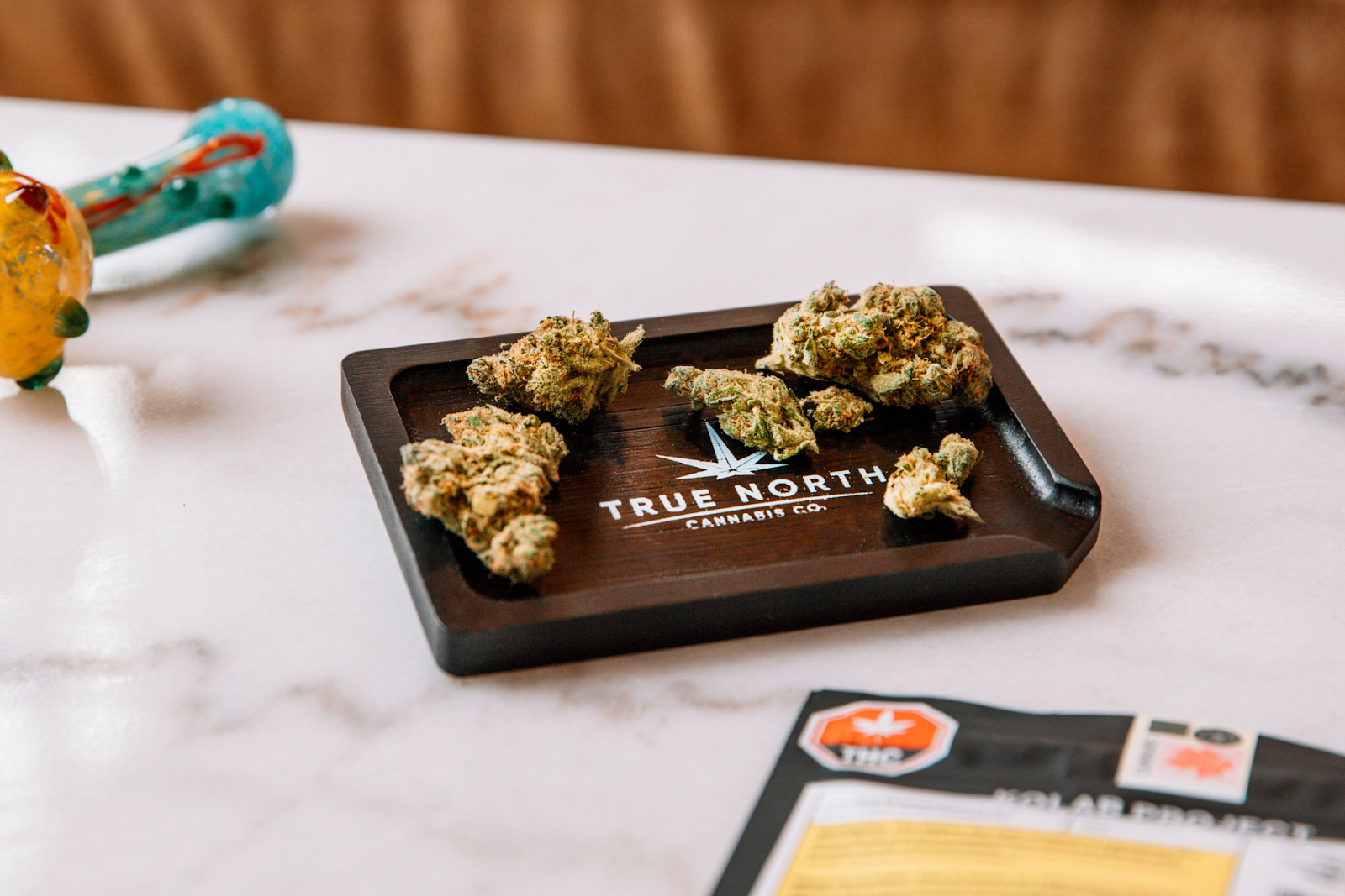 cannabis flowers on a tray next to a pipe