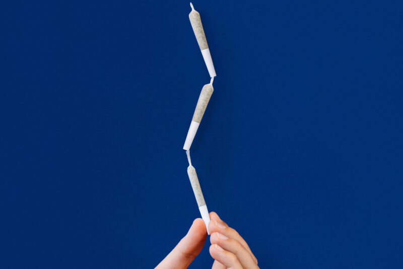 three pre-rolls balanced on top of each other on a blue background
