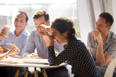A group of friends laughing and eating a pizza