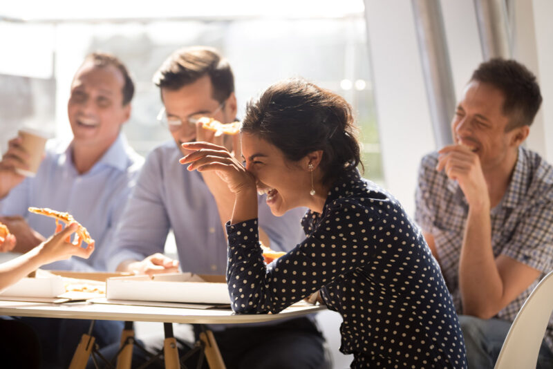 A group of friends laughing and eating a pizza