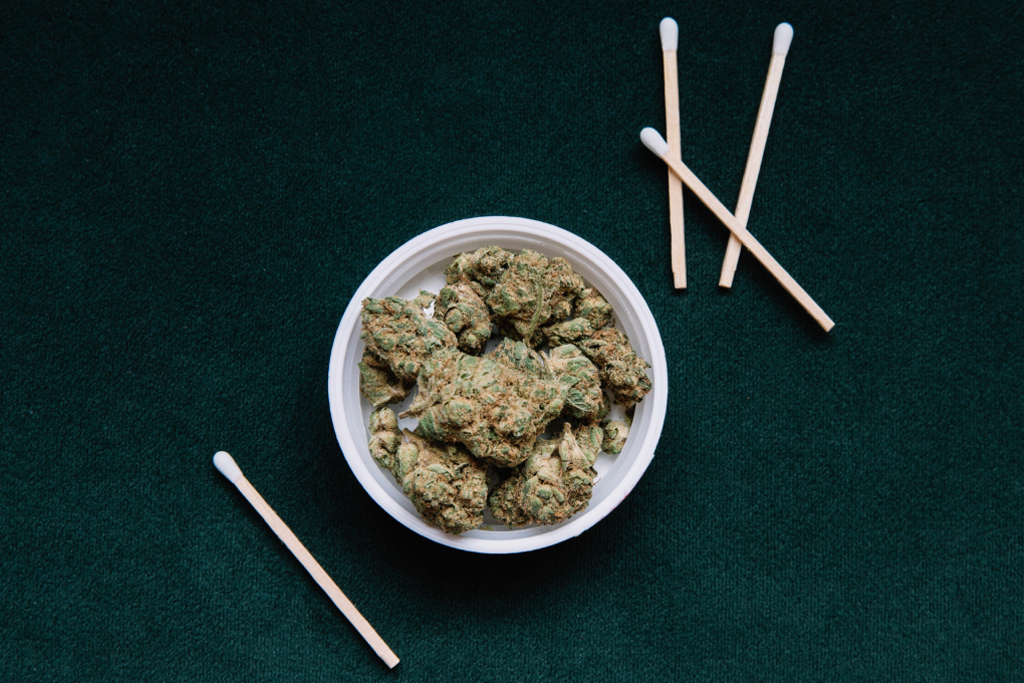 a container filled with cannabis flower with white matches surrounding it
