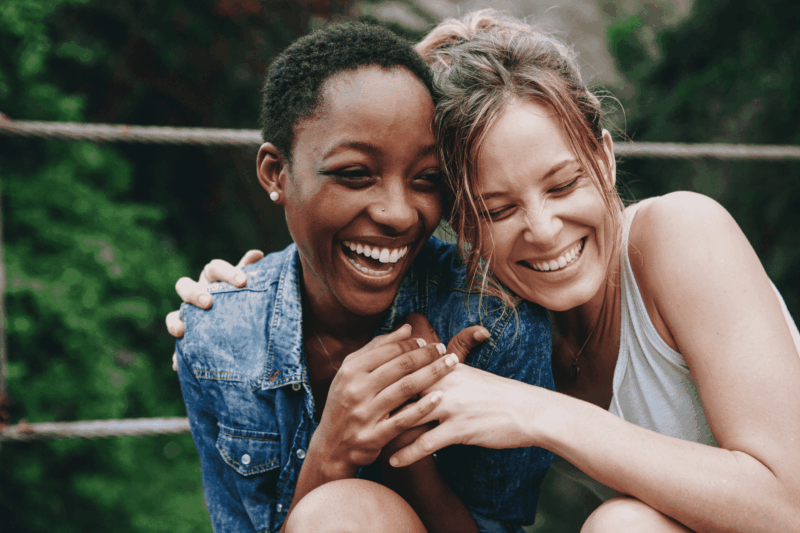 Two women laughing together outside in the summer