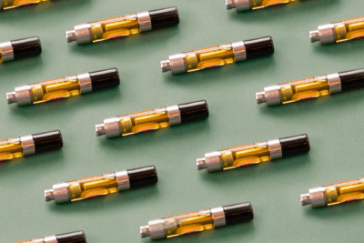 A flat lay of multiple vape cartridges on a green background