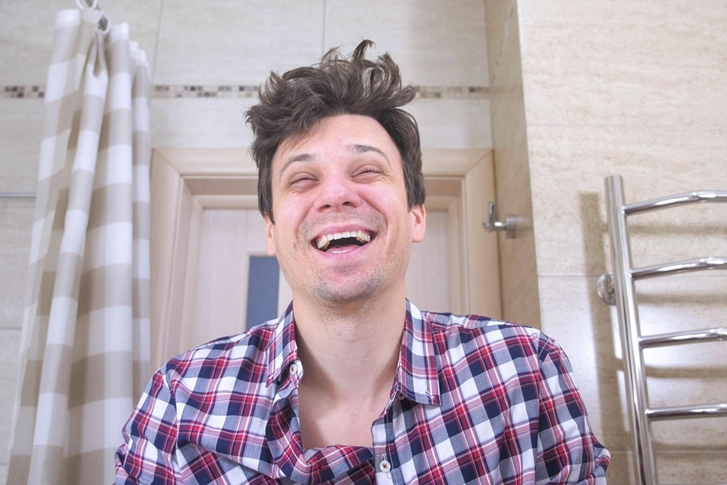 Young man with a high laughing at his reflection in the mirror