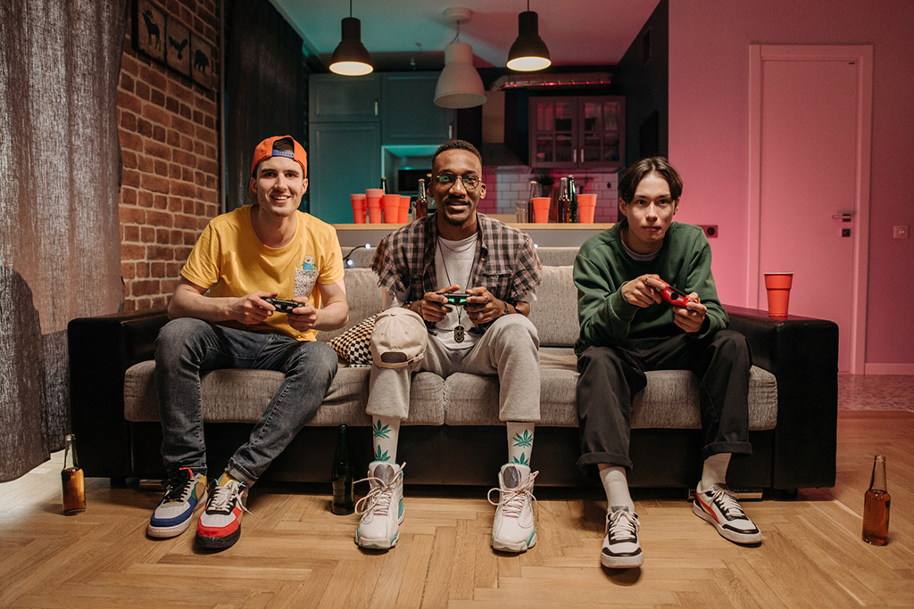a group of friends sit on a couch playing video games
