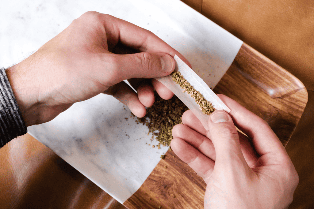 A person rolling a joint with freshly ground cannabis flower 