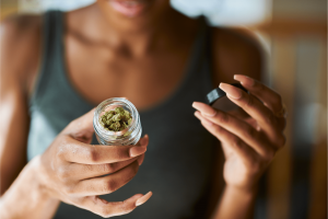 a woman holding a jar of cannabis buds
