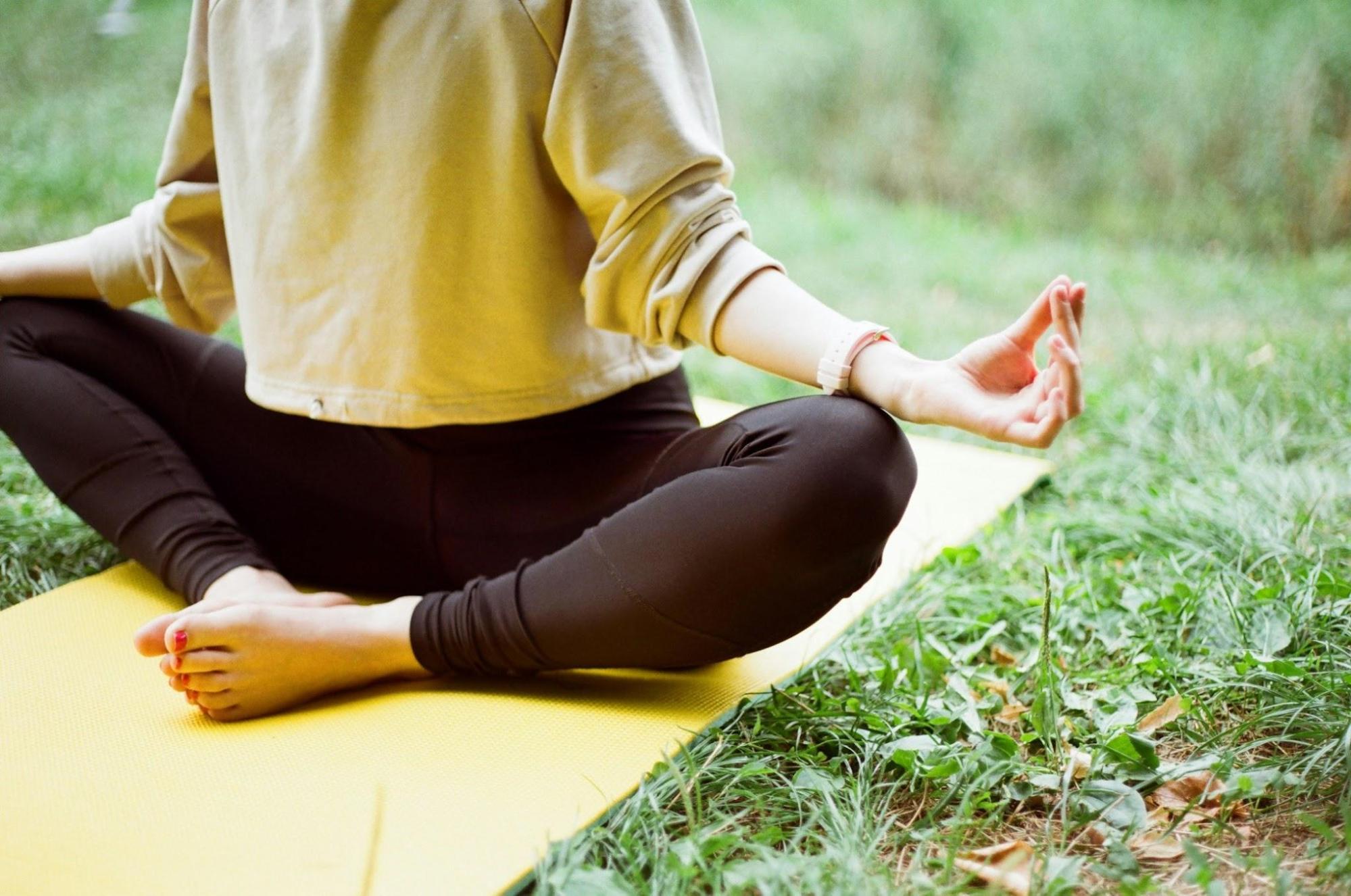 A person practicing mindfulness outside on a yoga mat