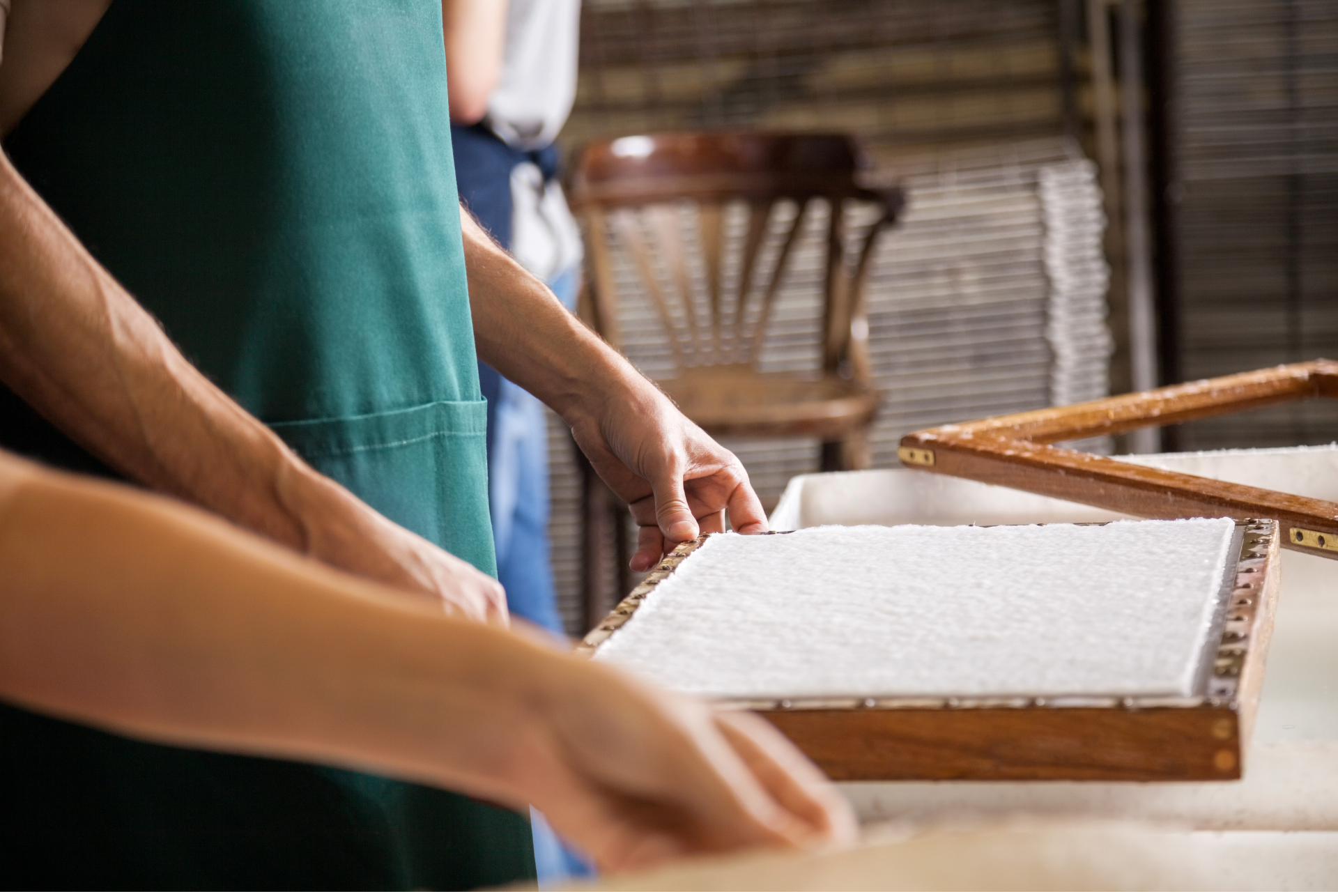 Two people using a mould and deckle to create paper out of cannabis stems
