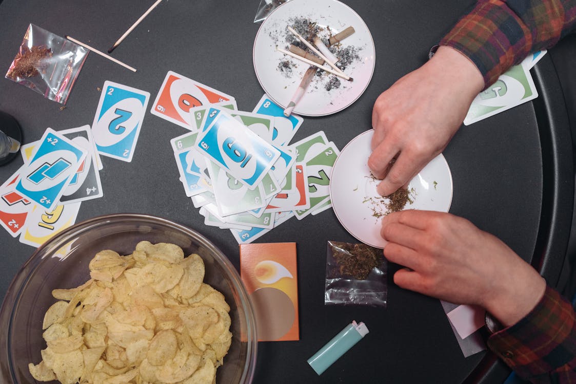 A pair of hands at a party table rolling up some cannabis