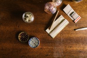 A weed grinder, dried cannabis flowers, rolling papers, and a pipe
