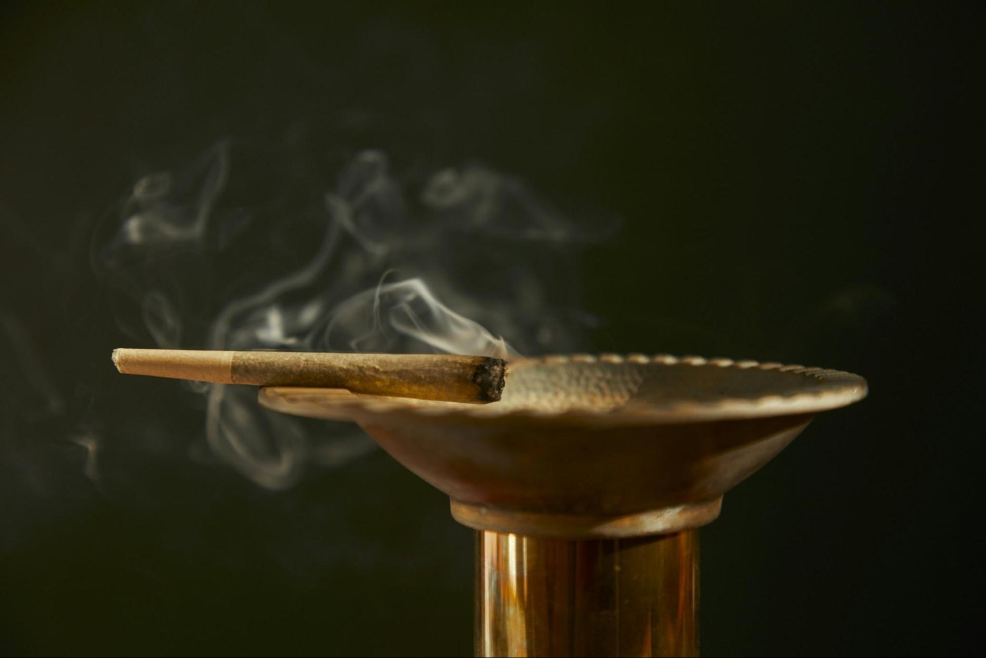 A pre-roll joint lit sitting on an ashtray