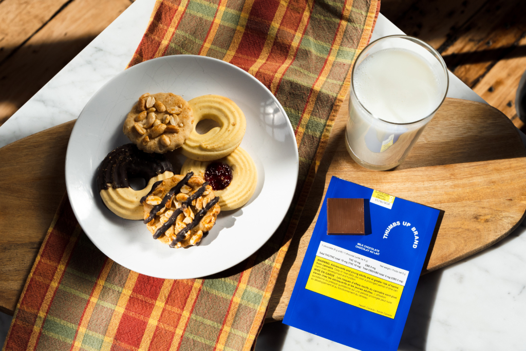 A spread of cannabis-infused edibles including cookies and chocolate on a table with a glass of milk