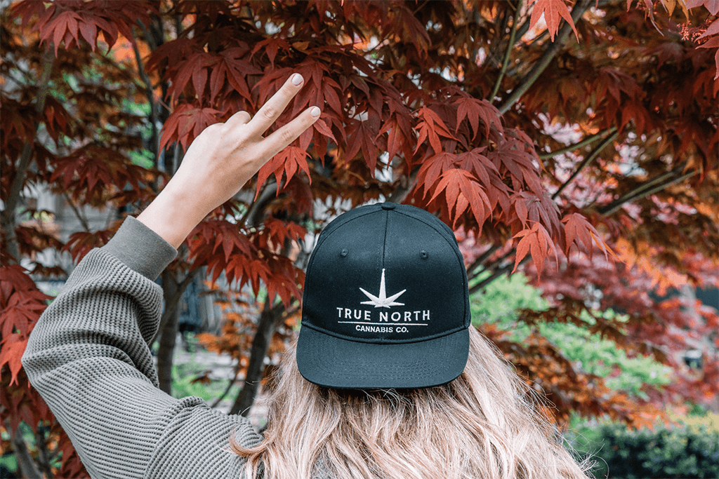A person wearing a True North Cannabis Co. cap flashing a “peace” sign