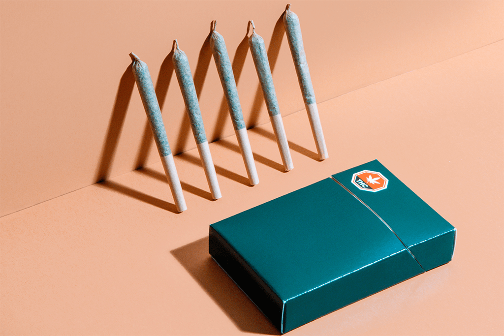 Five pre-rolls lined up against a wall with a box in front of them