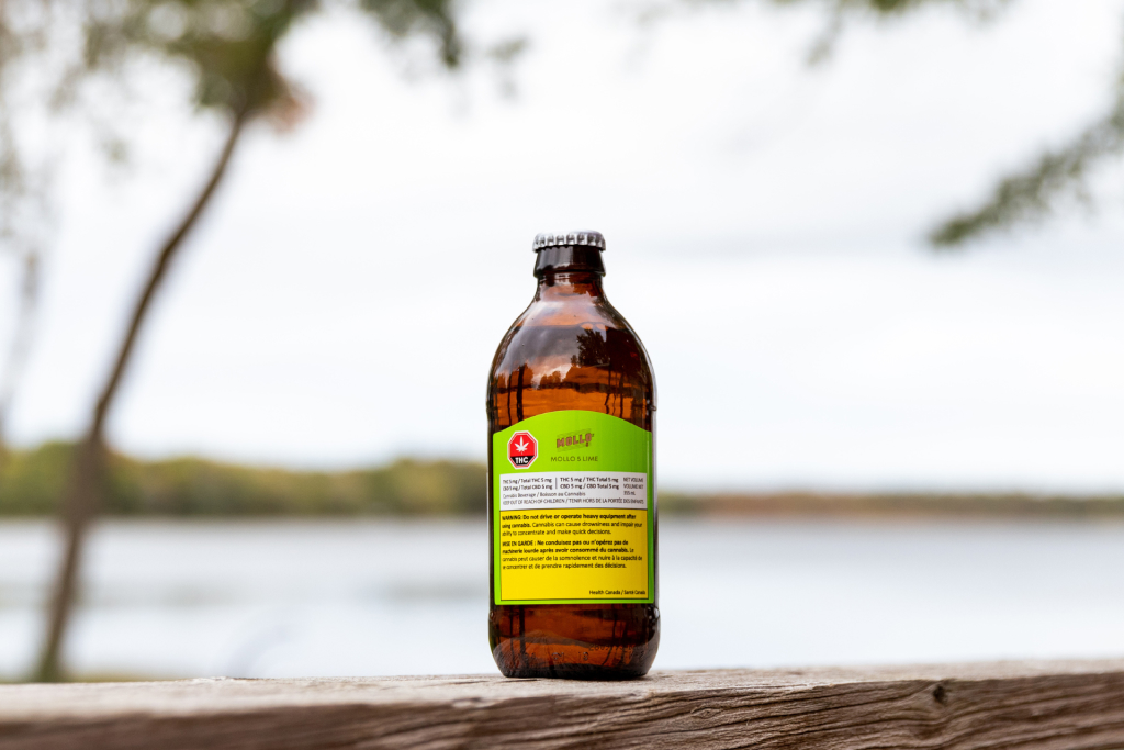 A close-up of Mollo 5 Lime cannabis-infused beverage positioned on a wood railing