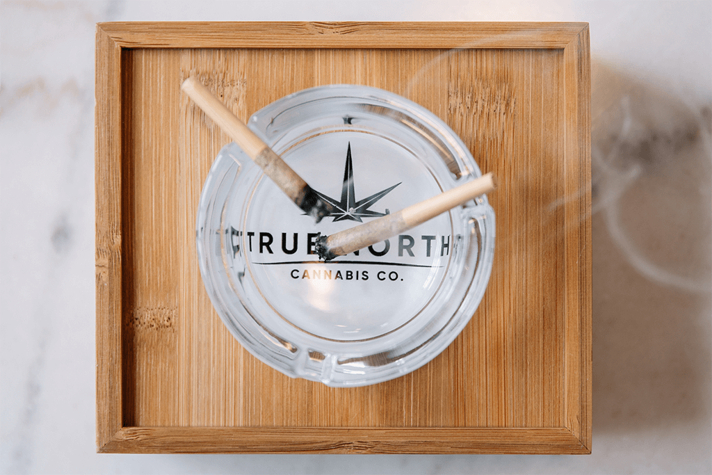 Two lit pre-rolls on top of a True North Cannabis Co. ashtray