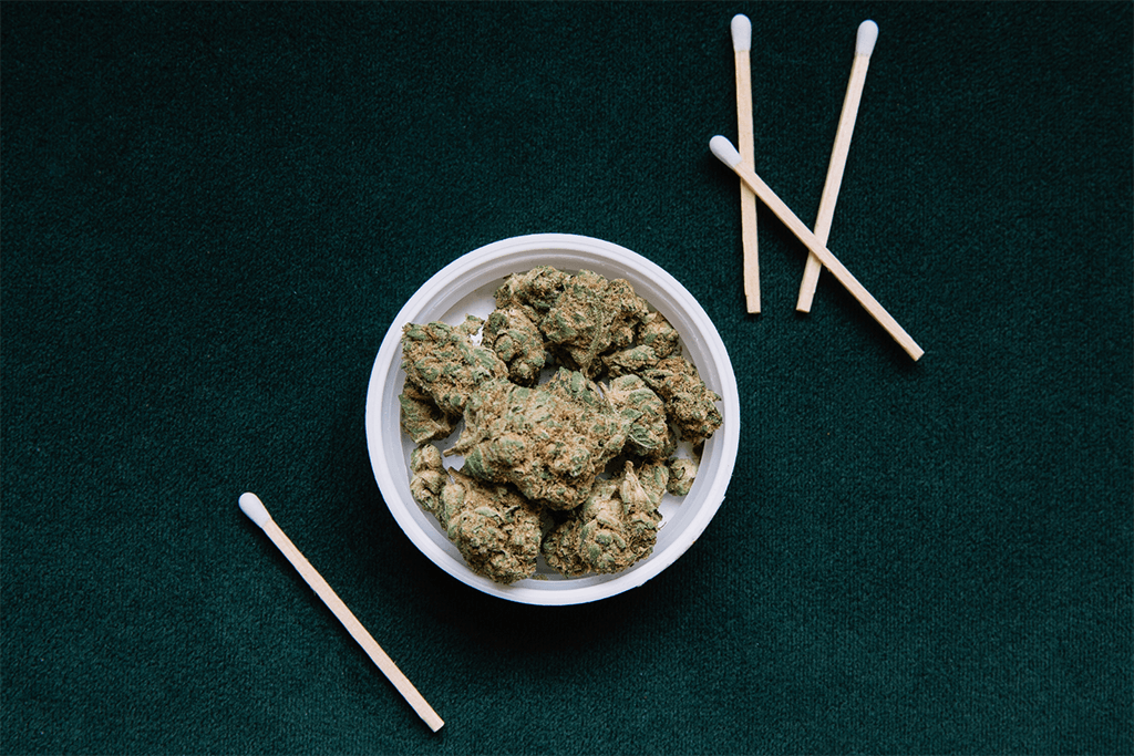 A flat lay of cannabis in a bowl and matchsticks 