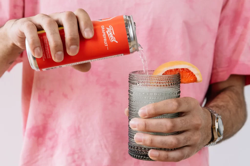 A person pouring a can of cannabis-infused beverage into a glass