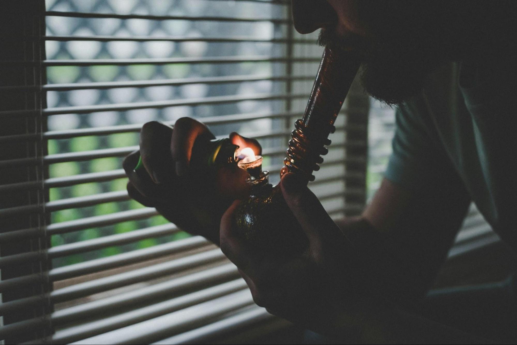 A man taking a toke of cannabis from a bong