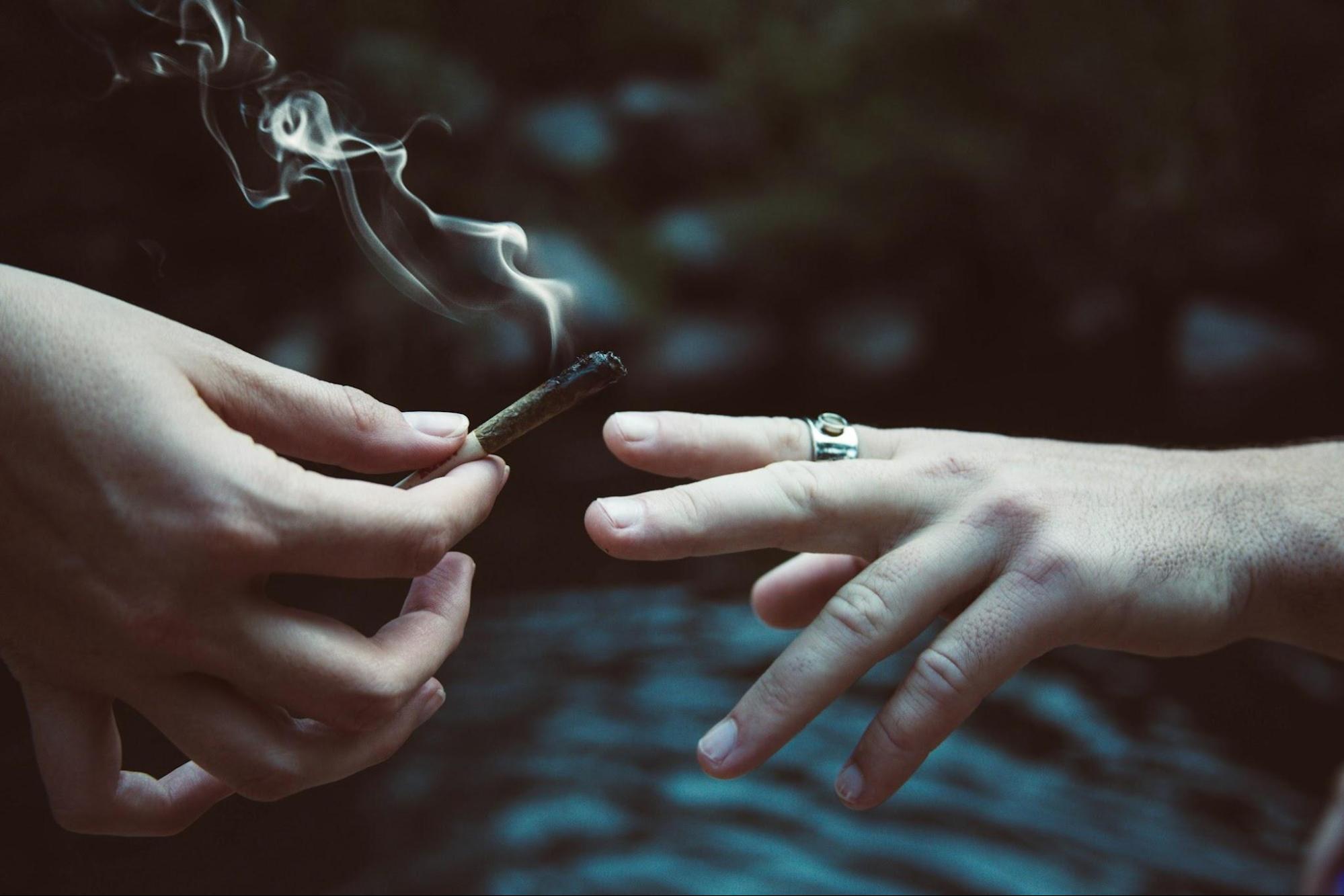 A cannabis joint being passed between two hands