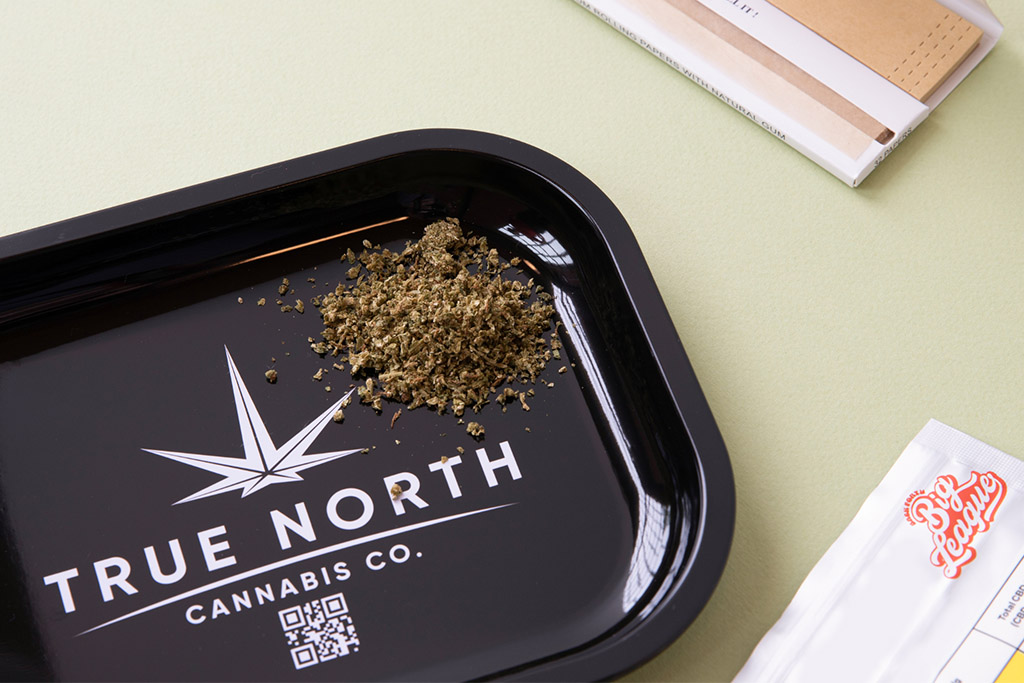 A True North rolling tray sitting on a table with some milled cannabis in it