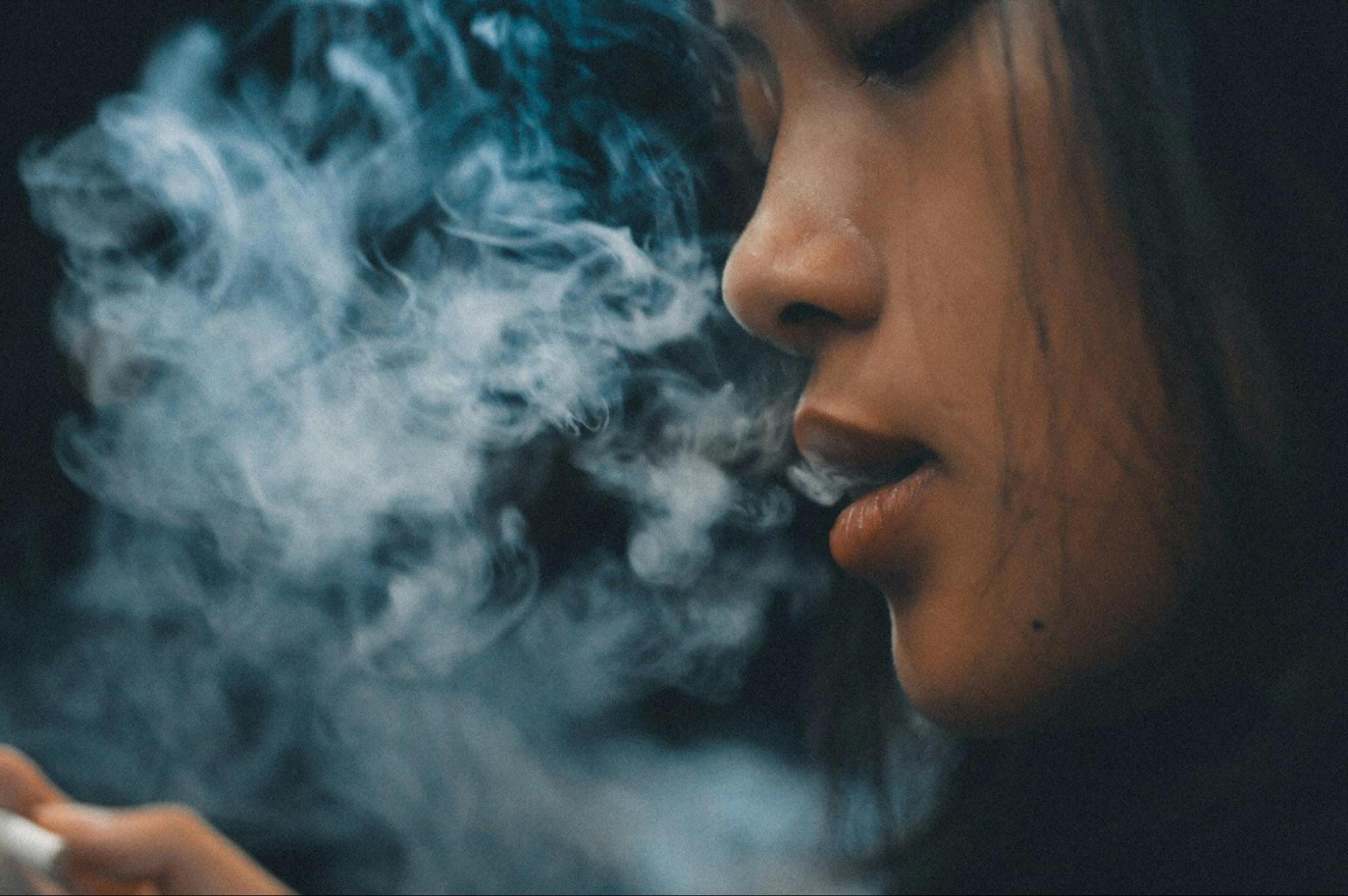 A woman exhaling a cloud of cannabis smoke