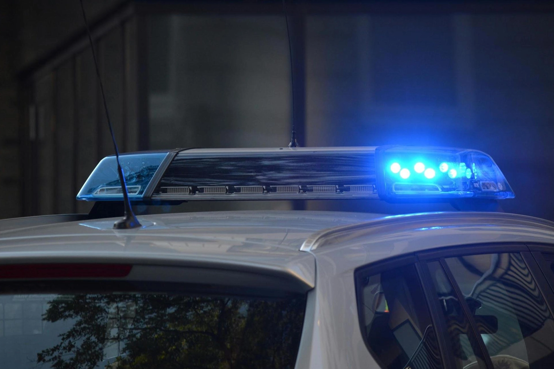 Close-up of a police car with blue emergency lights flashing, representing cannabis-related law enforcement.