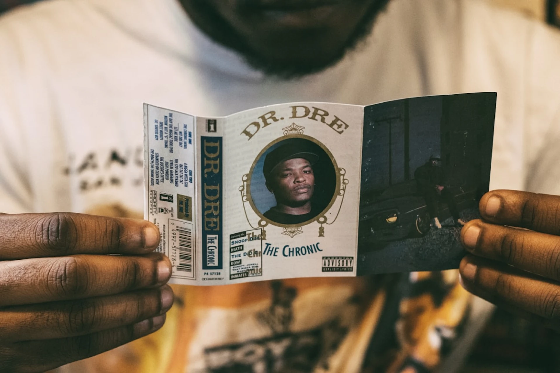 A man holding the insert of a cassette tape for Dr. Dre’s The Chronic